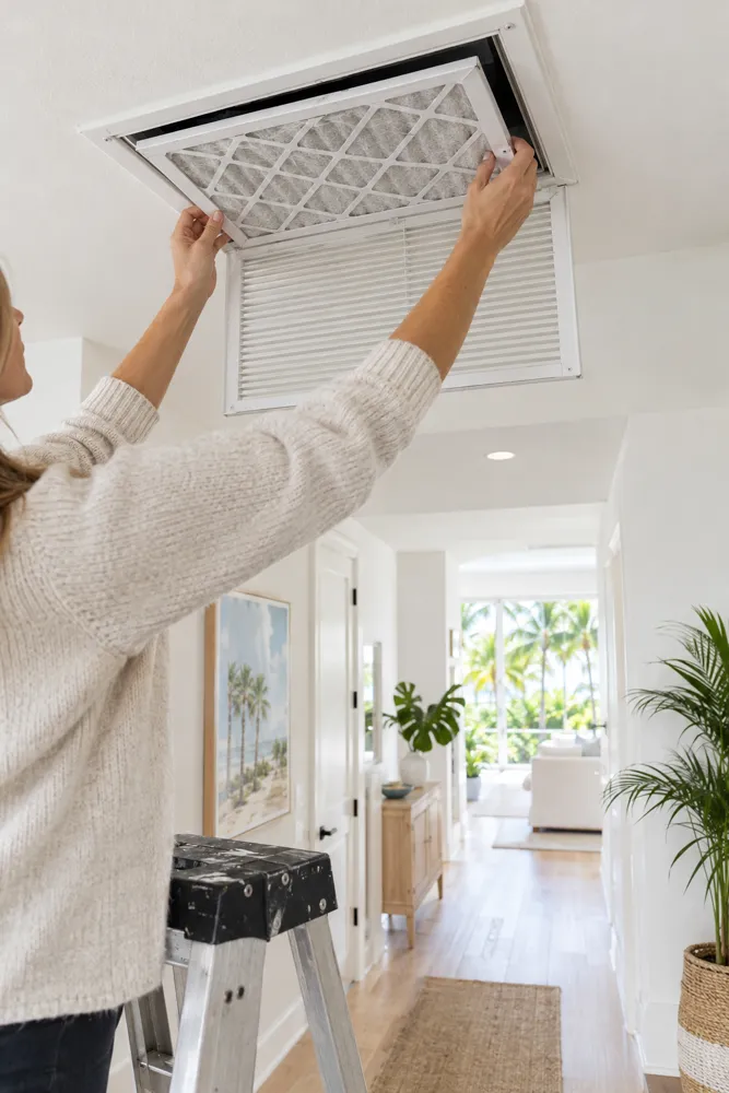 Woman changing the air-conditioning return filter in a ceiling vent
